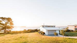 Une maison moderne avec un garage, une petite allée et une vue sur la mer.
