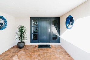 A modern entrance with a dark blue door, a potted plant, and two blue wall decorations. - Dockside on Mandurah Canals (Mandurah)