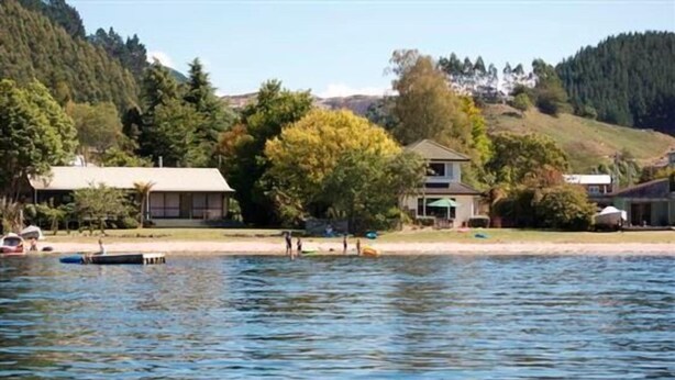 Una propiedad frente al lago con una casa, un muelle y un bote.