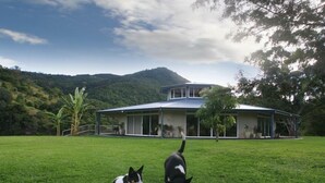 Una casa con un amplio jardín delantero, rodeada de árboles y colinas.