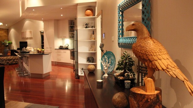 Una cocina moderna con armarios blancos, una zona de comedor de madera y una escultura decorativa de un pájaro de madera.