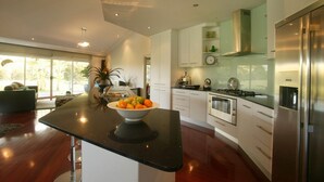 Una cocina moderna con una isla central, electrodomésticos de acero inoxidable y vistas al exterior.