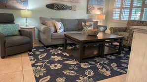A living room with a sofa, armchairs, a coffee table, and decorative wall art.