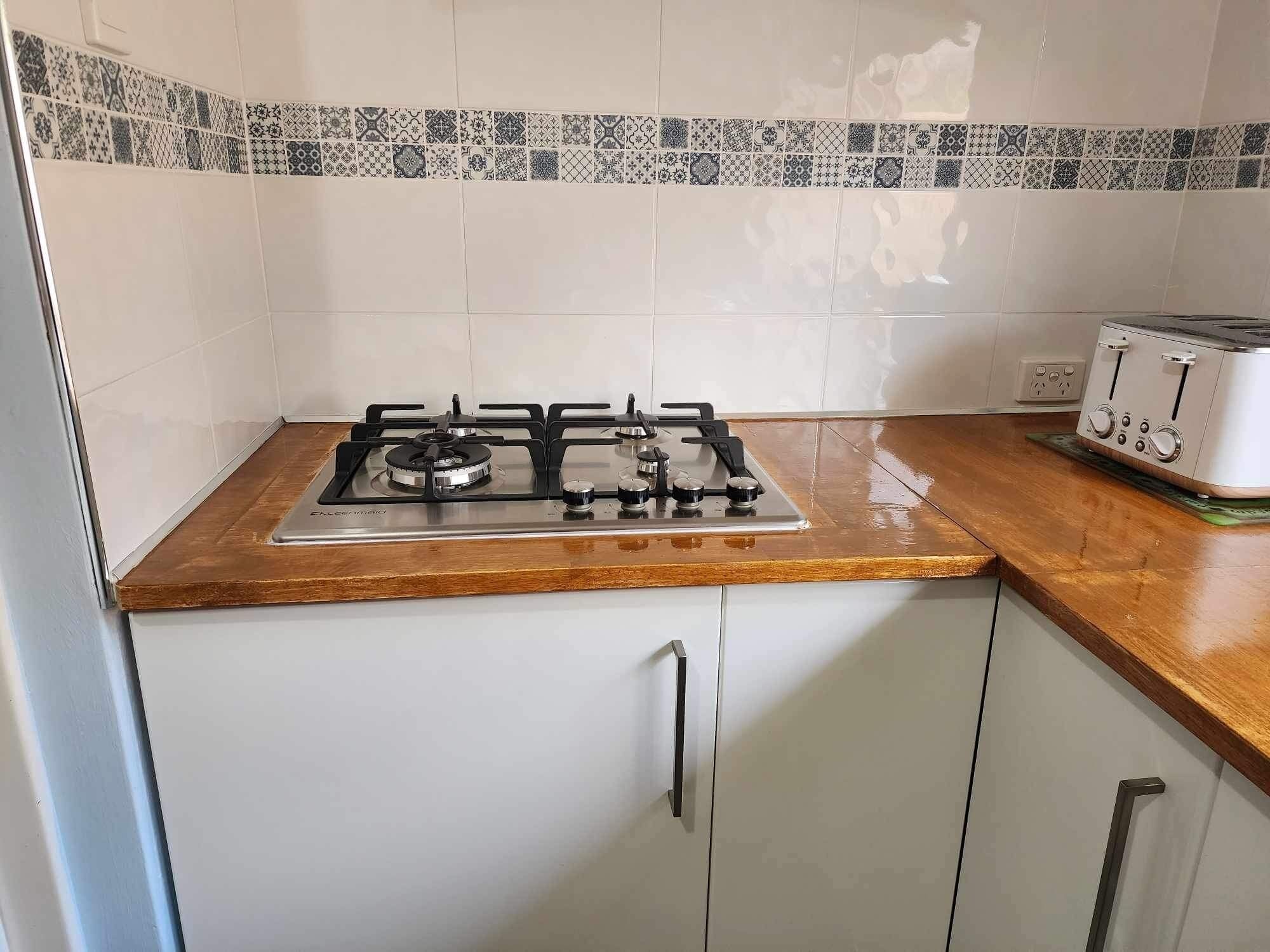 A kitchen with a gas stove, a toaster, and a patterned backsplash.