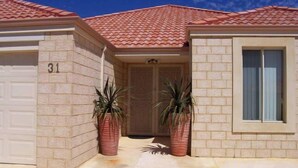 A single-story house with a red-tiled roof, beige brick exterior, and a garage door marked with the number 31.