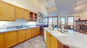 A kitchen with wooden cabinets, granite countertops, a built-in stove, and a stone fireplace.