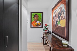 A hallway with a wooden bench, a framed painting, and a potted plant.
