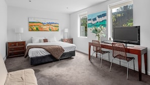 A bedroom with a bed, desk, TV, and artwork. - Lalique Elwood Beachside Apartment (Elwood)