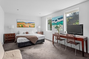 A bedroom with a bed, desk, TV, and artwork. - Lalique Elwood Beachside Apartment (Elwood)