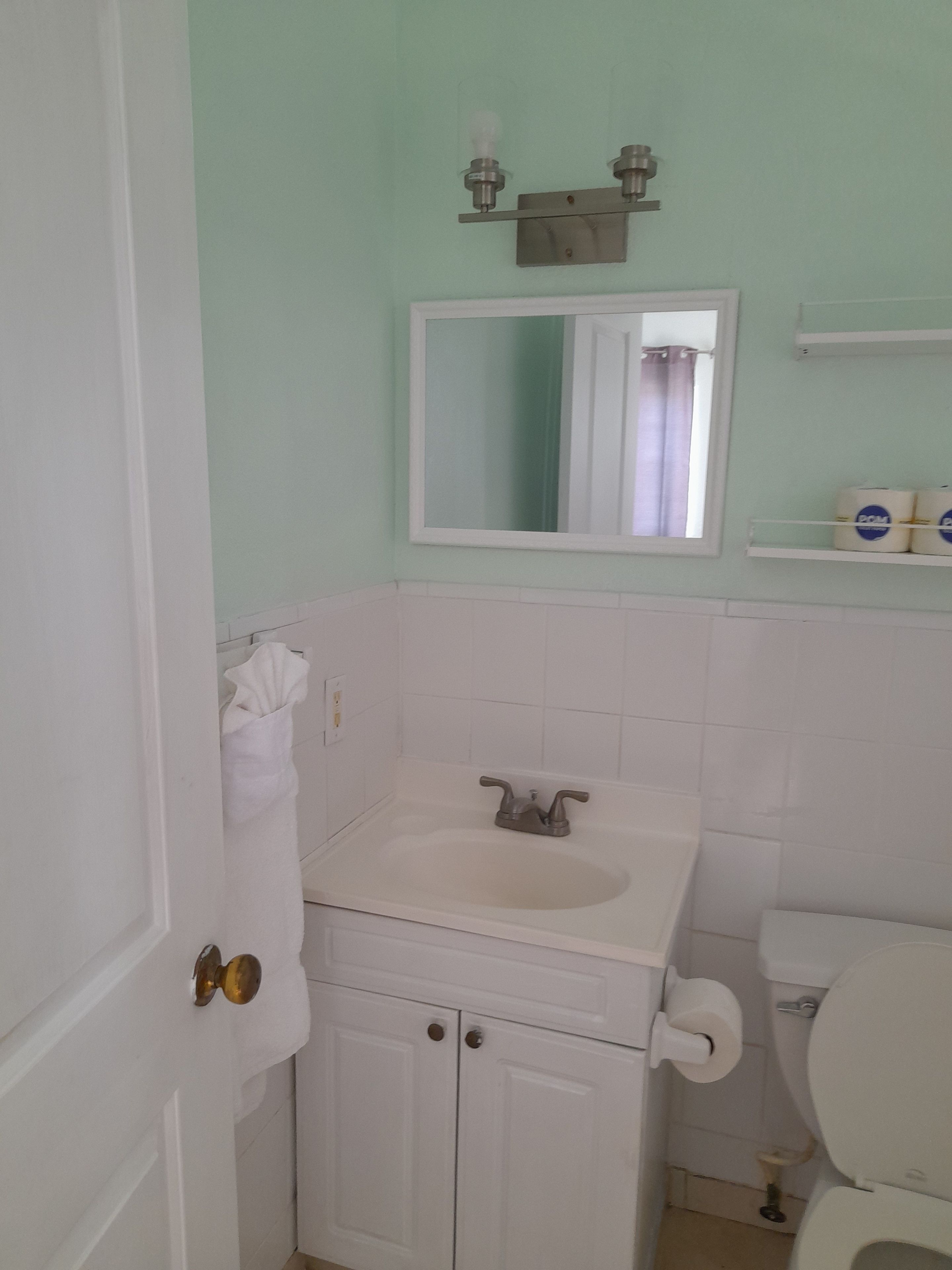 A bathroom with a sink, mirror, toilet, and a towel rack.