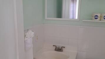 A bathroom with a sink, mirror, toilet, and a towel rack.