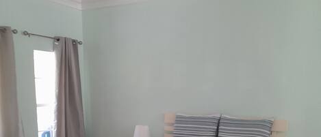 A bedroom with a bed, bedside tables, a window with curtains, and a ceiling fan.
