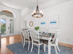 A dining area with a white table, chairs, and a patterned rug.
