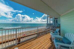 A wooden deck with a view of the beach and ocean.