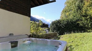 Uma banheira de hidromassagem em um jardim com vista para as montanhas.