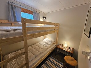 Une chambre avec un lit superposé, un bureau, une chaise et une petite table avec une lampe.