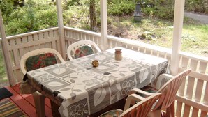 Un patio exterior con una mesa cubierta con mantel floreado, rodeado de sillas con cojines estampados.