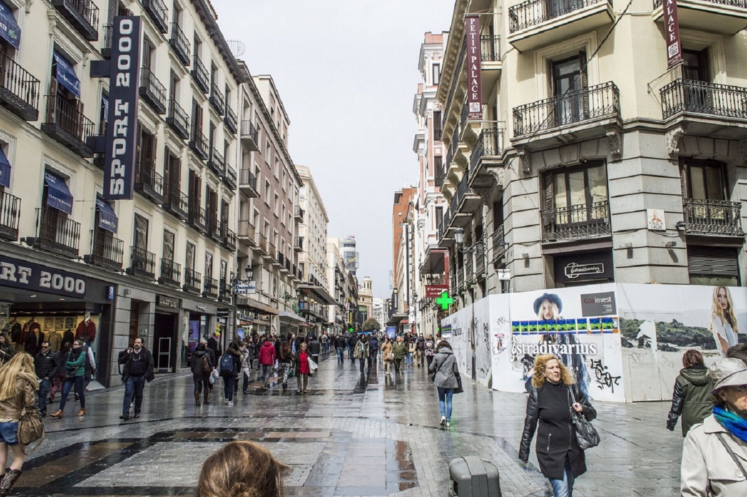 A busy urban street with pedestrians, shops, and buildings.