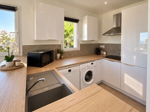 A modern kitchen with a built-in washing machine, a microwave, and a sink. - New apartment with magnificent view of Roya beach PROMO October November (Saint-Florent)