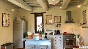 A kitchen with a central island, stainless steel appliances, and a hanging light fixture.