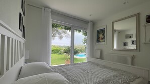 Quarto com uma cama grande, uma porta de correr para uma varanda e um espelho grande na parede.