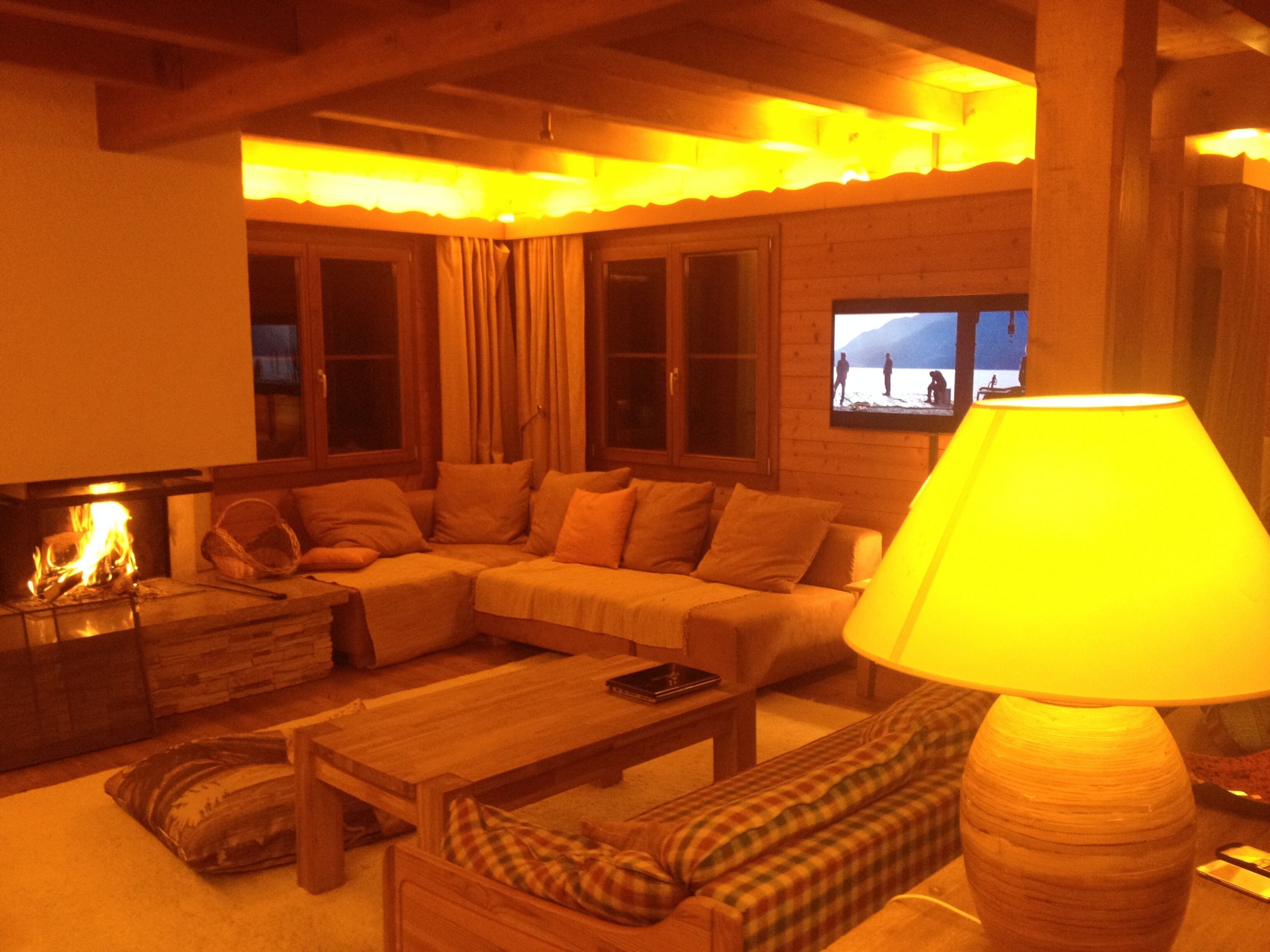 A cozy living room with a fireplace, a sofa, a coffee table, and a lamp.