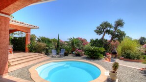 Una piscina circondata da un patio con una scalinata che conduce a un'area coperta con posti a sedere.