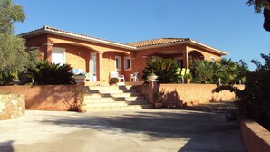 Una casa a due piani con facciata in pietra, tetto in tegole e un portico anteriore con posti a sedere all'aperto.