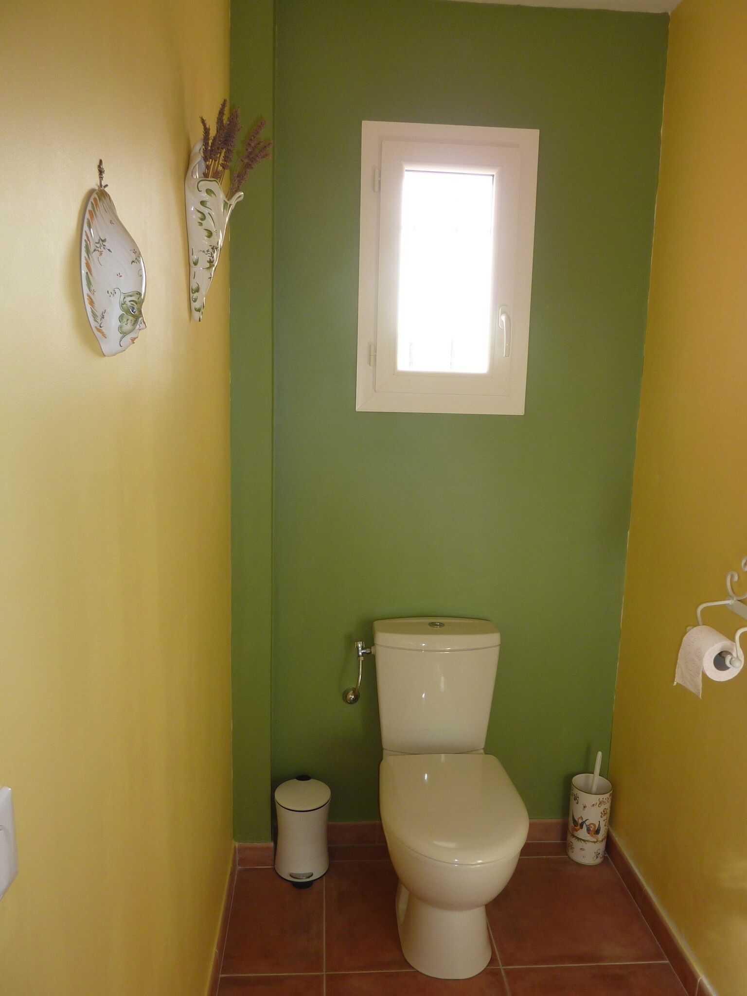 Un bagno piccolo con il water, un cestino e una finestra.