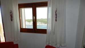 A room with a wooden-framed window, white curtains, and two red chairs. - House / Villa - Sant'Antioco (Sant'Antioco)