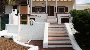 A house with a white exterior, a porch, and a set of wooden stairs leading to the entrance. - House / Villa - Sant'Antioco (Sant'Antioco)