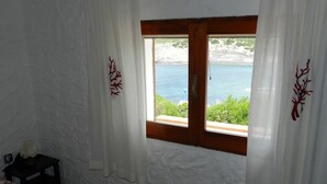 A room with white textured walls, a wooden window frame, and white curtains with red tree designs. - House / Villa - Sant'Antioco (Sant'Antioco)