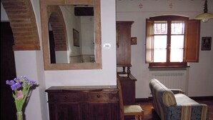 Una habitación con un armario de madera, un espejo, un sofá y una ventana con cortinas.