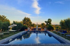 Ein rechteckiger Pool mit blauem Himmel und Bäumen im Hintergrund.