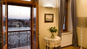 Un balcone con vista sul fiume e sulla città, un tavolo con un vaso di fiori e un quadro appeso al muro.