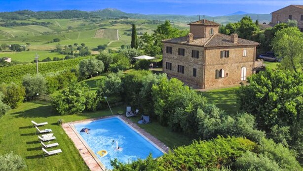 Una villa con piscina rodeada de exuberante vegetación y un paisaje montañoso.