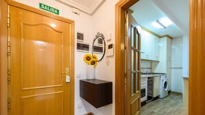 A hallway leading to a kitchen with a washing machine and dryer, a mirror with sunflowers, and a 'SALIDA' sign on a door. - Downtown Madrid North Barrio del Pilar. Tempory (Madrid)