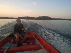 A person in a small red boat on a body of water with a forested island in the background. - Cozy cottage near the lake, including free Wi-Fi and own rowing boat (Hallaryd)