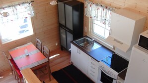 Une cuisine compacte équipée d’un évier, d’une cuisinière et d’un réfrigérateur. Un coin repas avec une table et des chaises est également disponible.