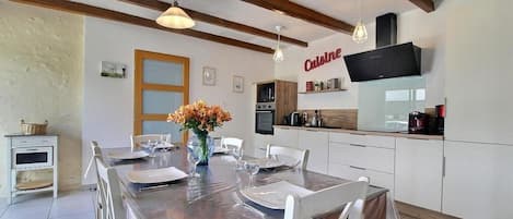 A modern kitchen with white cabinets, a built-in oven, and a coffee machine.