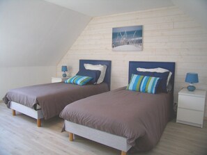 Ein Schlafzimmer mit zwei Betten, Holzboden und schrägen Wänden.