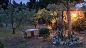 A garden with a stone table, a small bush, and a variety of plants. - L'ULIVETA DEL LUSCHI VILLA, PISCINA  E CAMPO DA TENNIS, WI-FI, PET FRIENDLY (ROSIGNANO MARITTIMO)