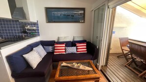 Un espacio de sala con un sofá azul oscuro, una mesa de centro de madera con dos tazas, y un cuadro enmarcado sobre el sofá.