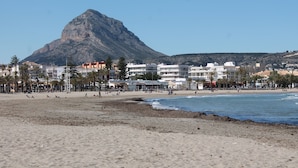 Une plage avec des bâtiments en arrière-plan et une montagne au loin.