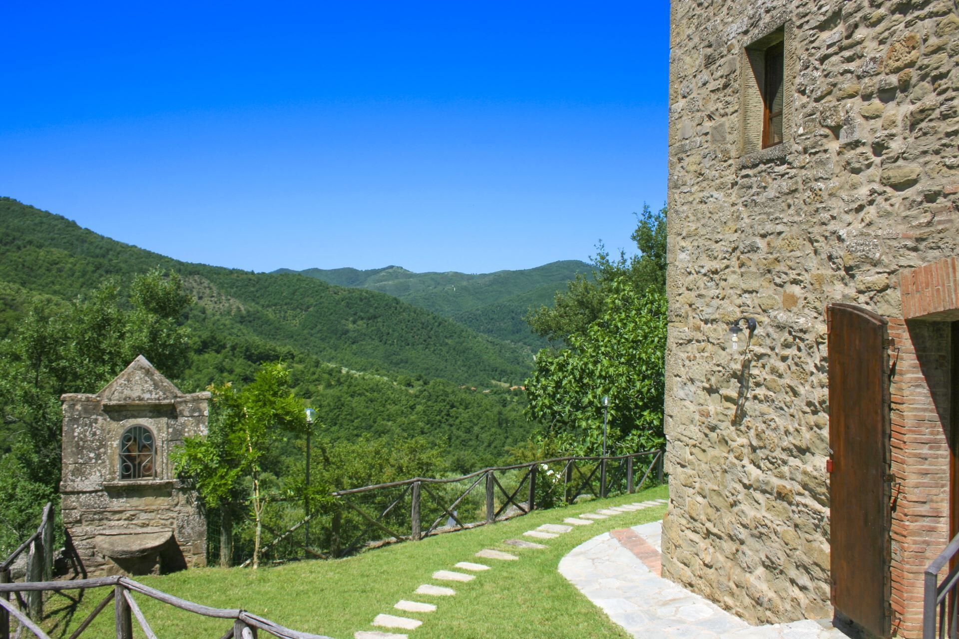 A stone building with a wooden door, a stone staircase, and a small tower with a window.
