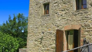 A stone building with a wooden door, a staircase, and a metal railing.