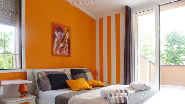 Ein Schlafzimmer mit einem Bett, einem Nachttisch, einem Fenster und einem Bild an der Wand.