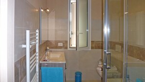 Ein modernes Badezimmer mit Duschkabine aus Glas, einem weißen Waschbecken und einem Spiegel darüber.