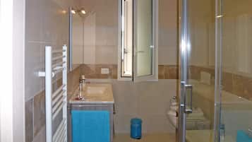 A modern bathroom with a glass shower enclosure, a white sink, and a mirror above the sink.