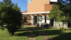 Ein modernes Haus mit flachem Dach, großen Fenstern und einer überdachten Terrasse.